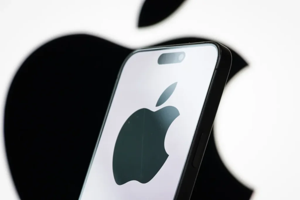In this photo illustration, the logo of Apple Inc. is displayed on a smartphone screen, with the company's iconic black apple symbol visible in the background.