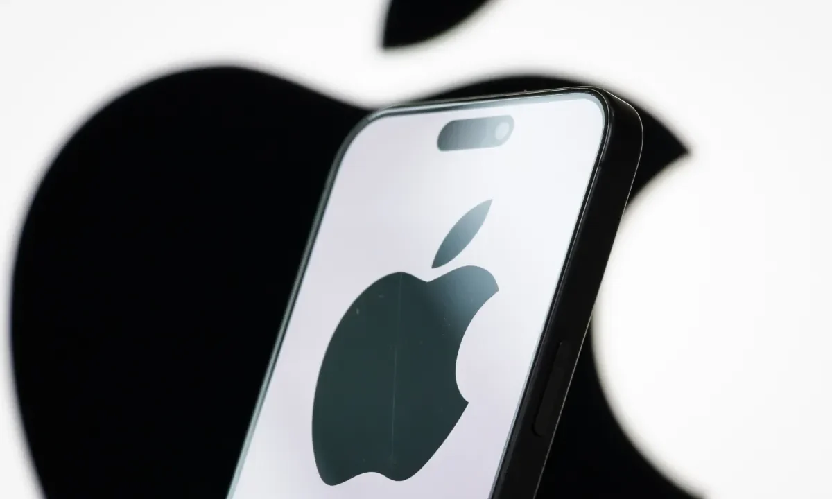 In this photo illustration, the logo of Apple Inc. is displayed on a smartphone screen, with the company's iconic black apple symbol visible in the background.