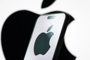 In this photo illustration, the logo of Apple Inc. is displayed on a smartphone screen, with the company's iconic black apple symbol visible in the background.