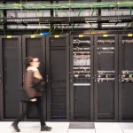 A visitor walks past a computer bay at the PA10 data center, operated by Equinix Inc., in Paris, France.