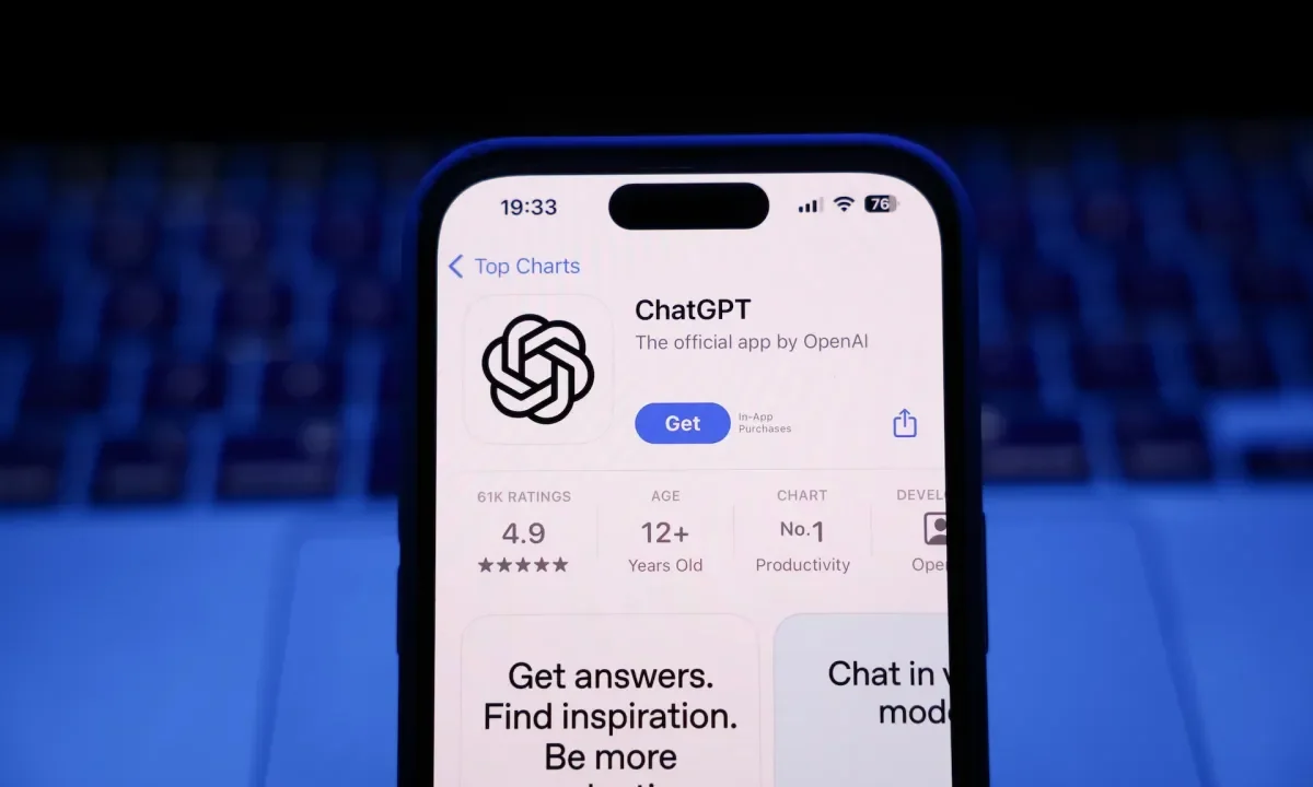 A laptop keyboard and ChatGPT on App Store displayed on a phone screen.