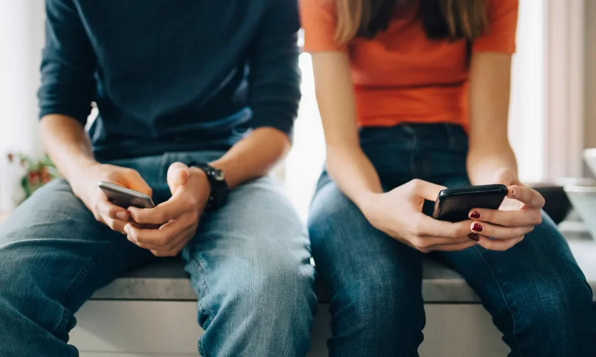 couple sitting, texting on smartphones