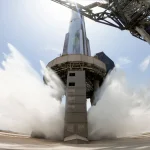 A view of SpaceX's starship system on the launchpad with the water-cooling flame deflector system active