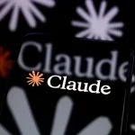 The Claude logo is displayed on a smartphone screen placed on a reflective surface onto which a multitude of Claude logos are projected.