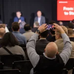 An attendee at a StrictlyVC 2025 event taking a photograph
