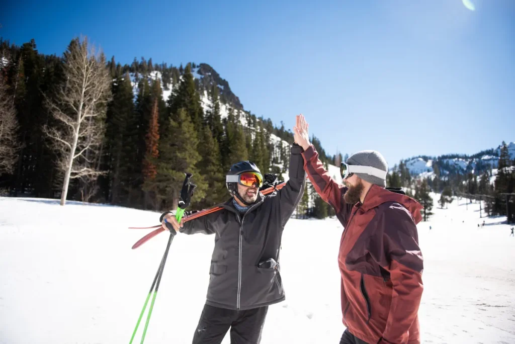 Two friends high-fiving while skiing.