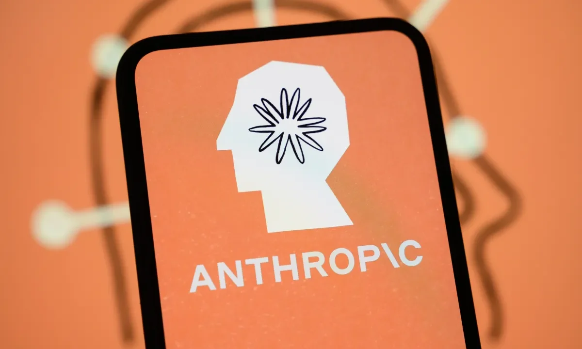 The Anthropic logo is displayed on the screen of a smartphone with the company's branding in the background.