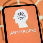 The Anthropic logo is displayed on the screen of a smartphone with the company's branding in the background.