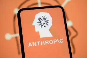 The Anthropic logo is displayed on the screen of a smartphone with the company's branding in the background.