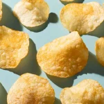 Potato chips sit against a light blue table.